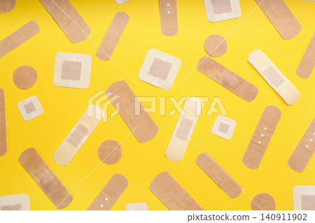 Different types of sticking plasters on yellow background, flat lay Different types of sticking plasters on yellow background, flat lay 140911902