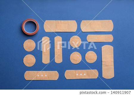 Different types of sticking plasters on blue background, flat lay Different types of sticking plasters on blue background, flat lay 140911907