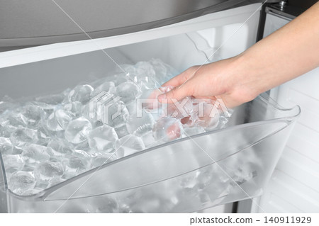 Woman taking plastic bag with ice cubes from fridge, closeup 140911929