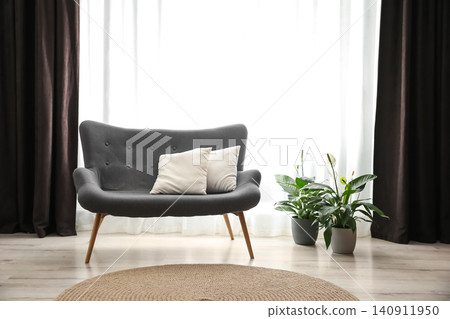 Comfortable sofa near window with elegant curtains in room Comfortable sofa near window with elegant curtains in room 140911950