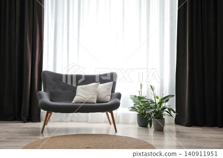 Comfortable sofa near window with elegant curtains in room Comfortable sofa near window with elegant curtains in room 140911951