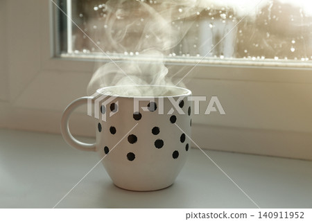 Cup of hot drink near window on rainy day Cup of hot drink near window on rainy day 140911952