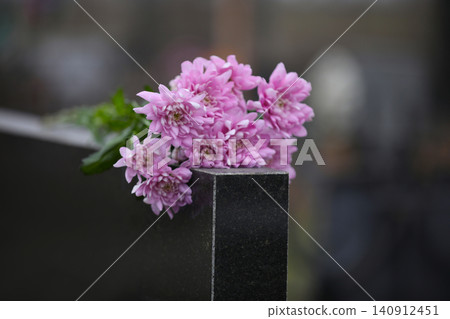 Chrysanthemum flowers on black granite tombstone outdoors. Funeral ceremony Chrysanthemum flowers on black granite tombstone outdoors. Funeral ceremony 140912451