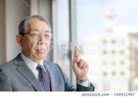 一位老人在窗邊舉起食指。 一位老人在窗邊舉起食指。 140912467