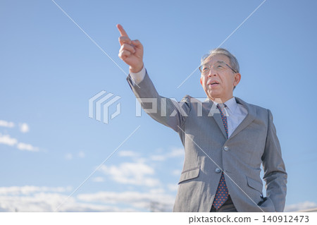 A senior man points to the future under a blue sky. 140912473