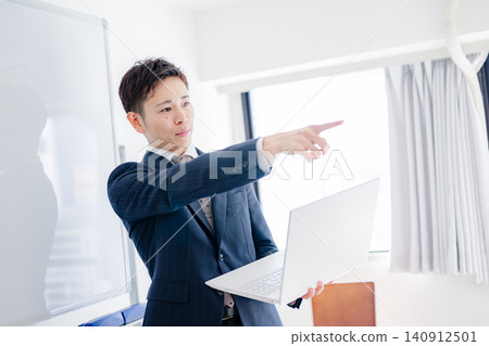 一名男子拿著筆記型電腦,指著螢幕進行解釋。 一名男子拿著筆記型電腦,指著螢幕進行解釋。 140912501