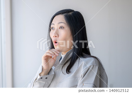 A woman in work clothes with a surprised expression. 140912512
