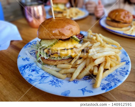 A hearty cheeseburger and French fries set from a cafe. A hearty cheeseburger and French fries set from a cafe. 140912591