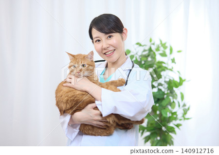 A female veterinarian smiles while holding a cat. A female veterinarian smiles while holding a cat. 140912716