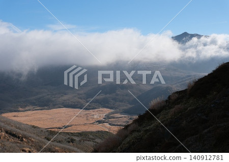 藍天之下，一片白雲升騰而起，覆蓋了山坡和紅褐色的盆地。 140912781