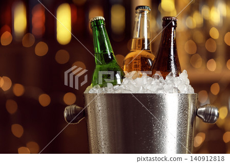Beer in metal bucket with ice against blurred lights, closeup 140912818
