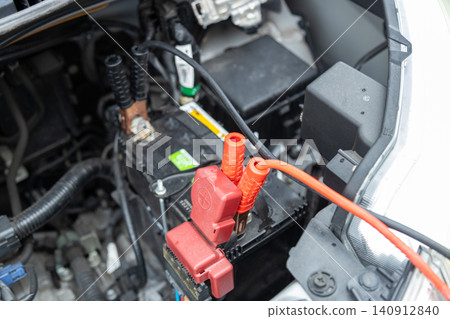 一張庫存照片,照片中一輛汽車正在幫助另一輛電瓶沒電的汽車;跨接電纜連接到電瓶上。 一張庫存照片,照片中一輛汽車正在幫助另一輛電瓶沒電的汽車;跨接電纜連接到電瓶上。 140912840