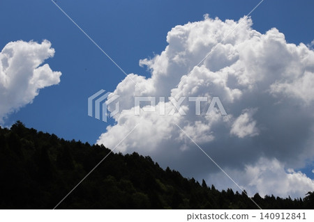 夏日天空,高聳的積雨雲和翠綠的山巒。 夏日天空,高聳的積雨雲和翠綠的山巒。 140912841