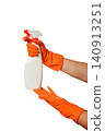 hands in orange gloves squeeze a white spray bottle from below and above 140913251