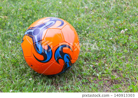 Orange soccer ball on a grassy field with copy space and natural daylight Orange soccer ball on a grassy field with copy space and natural daylight 140913303