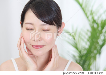 一位女子閉上眼睛,撫摸臉頰,感受濕潤。 一位女子閉上眼睛,撫摸臉頰,感受濕潤。 140913394