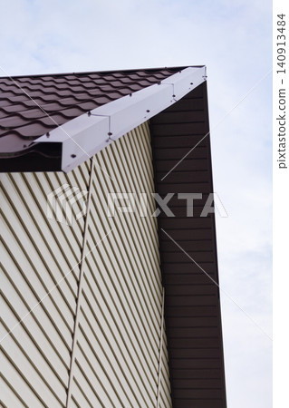 Low angle view of house corner with metal roof and vinyl siding Low angle view of house corner with metal roof and vinyl siding 140913484