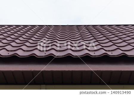 Brown metal roof with profiled roofing panels against cloudy sky Brown metal roof with profiled roofing panels against cloudy sky 140913490