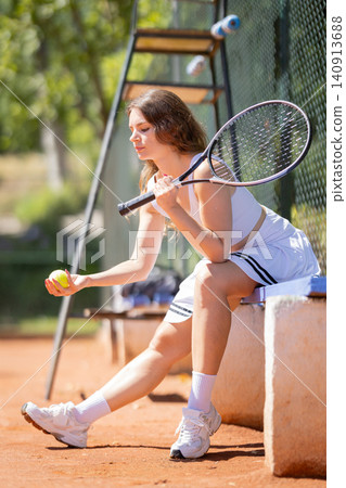 Tennis player prepares to serve on a clay court under bright sunshine in the early afternoon Tennis player prepares to serve on a clay court under bright sunshine in the early afternoon 140913688