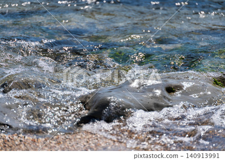 The sandy beach at the waterline and the wet rocks The sandy beach at the waterline and the wet rocks 140913991