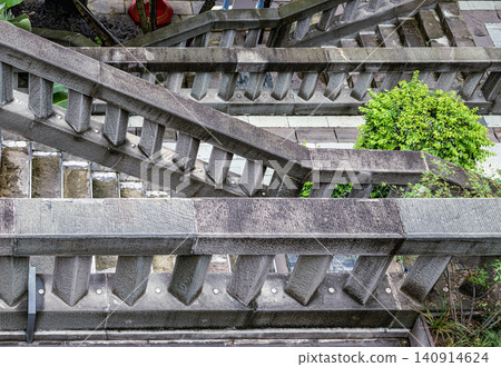 High-angle architectural abstract of interlocking stone staircases, severe angles, and geometric balustrades in a modern urban landscape. High-angle architectural abstract of interlocking stone staircases, severe angles, and geometric balustrades in a modern urban landscape. 140914624