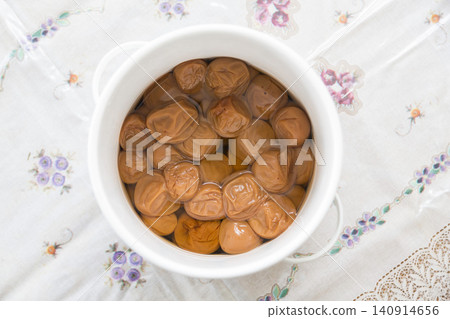 A bird's-eye view of Japanese food, showing pickled plums in a white pot, photographed from directly above. A bird's-eye view of Japanese food, showing pickled plums in a white pot, photographed from directly above. 140914656