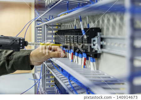An electrician's hands-on work: wiring relay terminals with a yellow screwdriver. An electrician's hands-on work: wiring relay terminals with a yellow screwdriver. 140914673