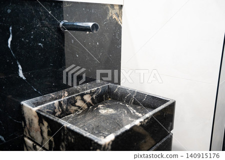Modern marble sink with wall mounted faucet in a contemporary commercial restroom. Premium bathroom interior and sanitary design for office and public facilities Modern marble sink with wall mounted faucet in a contemporary commercial restroom. Premium bathroom interior and sanitary design for office and public facilities 140915176