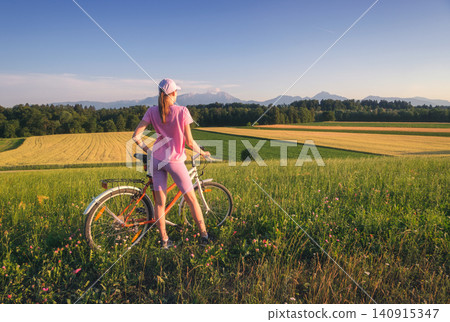 Woman on mountain bike on gravel road at sunset in summer Woman on mountain bike on gravel road at sunset in summer 140915347
