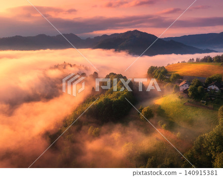 Aerial view of meadows and mountains in low clouds at sunrise 140915381
