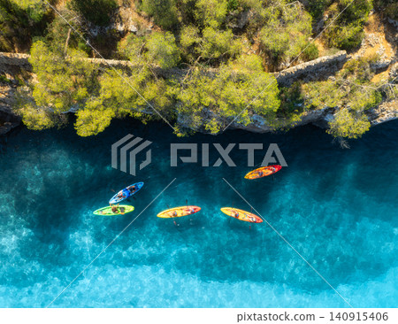 Aerial drone view of colorful kayaks, rocky coastline, blue sea 140915406