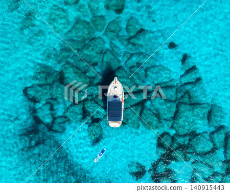 Aerial drone view of boat anchored in crystal clear turquoise sea 140915443