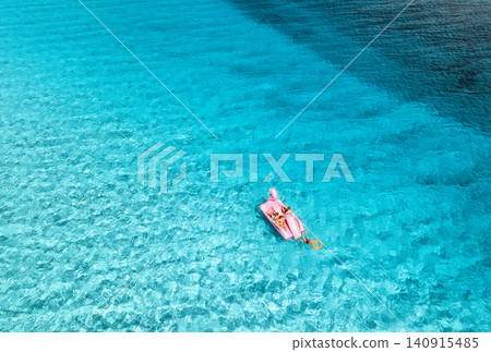 Aerial view of Inflatable pink flamingo in crystal clear blue sea Aerial view of Inflatable pink flamingo in crystal clear blue sea 140915485