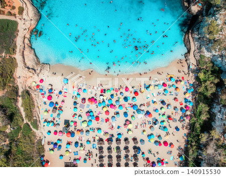 Aerial view of colorful umbrellas on sandy beach, swimming people Aerial view of colorful umbrellas on sandy beach, swimming people 140915530