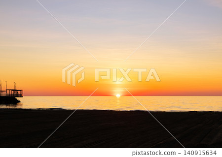 Vibrant orange sunset in the empty beach by the sea. Vibrant orange sunset in the empty beach by the sea. 140915634