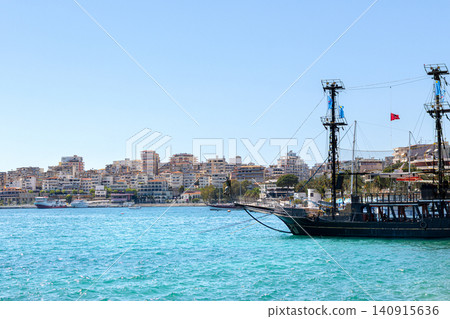 Black ship on the blue waters of Sarande marina in summer. Black ship on the blue waters of Sarande marina in summer. 140915636