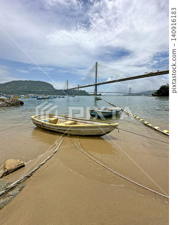 Serene coastal view with boats and bridge under a cloudy sky 140916183