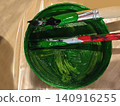 Green paint and brushes resting in container 140916255