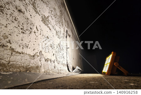 Portable floodlight illuminating damaged concrete wall at night Portable floodlight illuminating damaged concrete wall at night 140916258