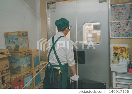 A male employee walking from the back room of a supermarket towards the sales floor. A male employee walking from the back room of a supermarket towards the sales floor. 140917366