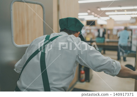 A store clerk greeting customers when they go out onto the supermarket floor. A store clerk greeting customers when they go out onto the supermarket floor. 140917371