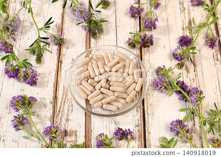 Alfalfa powder in capsules with a bouquet of flowers, a medicinal herbal composition, an alternative folk medicine concept, an advertisement for a green pharmacy, a collection of useful herbs 140918019
