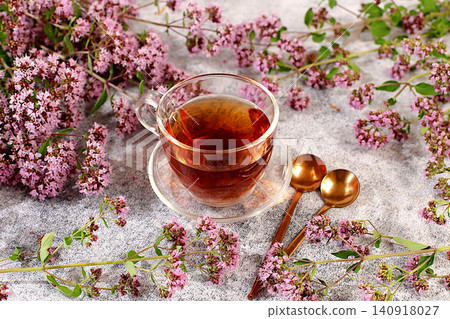 Medicinal herbal tea or Oregano infusion in a glass cup with flowers, alternative traditional medicine concept, estrogen source, menopause remedy, green pharmacy advertisement, Medicinal herbal tea or Oregano infusion in a glass cup with flowers, alternative traditional medicine concept, estrogen source, menopause remedy, green pharmacy advertisement, 140918027