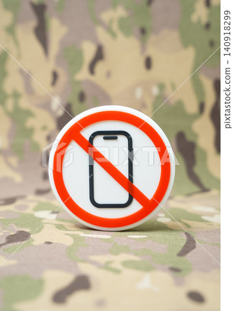 A symbol prohibiting phone use on a military background. Restrictions on smart devices at military facilities to prevent espionage and information leaks. A symbol prohibiting phone use on a military background. Restrictions on smart devices at military facilities to prevent espionage and information leaks. 140918299