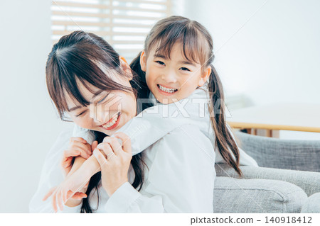 A little elementary school girl clinging to her mom A little elementary school girl clinging to her mom 140918412