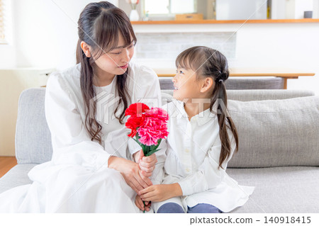 A little girl gives her mother a bouquet of carnations. A little girl gives her mother a bouquet of carnations. 140918415