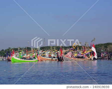 MUNCAR, INDONESIA - JULY 1, 2026: Traditional decorated fishing boats participate in the annual Petik Laut ceremony, a cultural sea offering and thanksgiving event held by the local fishermen communit MUNCAR, INDONESIA - JULY 1, 2026: Traditional decorated fishing boats participate in the annual Petik Laut ceremony, a cultural sea offering and thanksgiving event held by the local fishermen communit 140919030