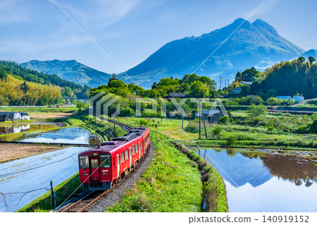 The KiHa 200 series train runs through the early summer countryside with Mount Yufu in the background on the Kyudai Main Line. The KiHa 200 series train runs through the early summer countryside with Mount Yufu in the background on the Kyudai Main Line. 140919152