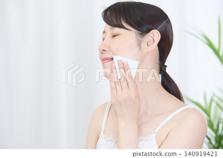 一位面帶微笑的日本女子用棉球擦拭臉頰。 140919421