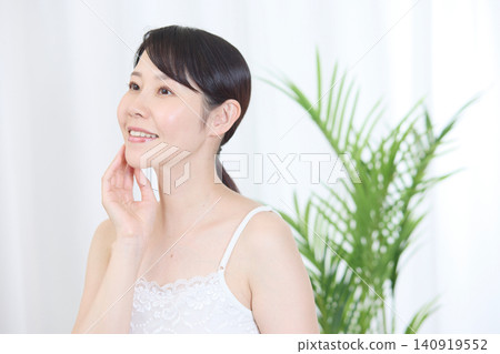 A woman with beautiful skin smiles while touching her cheek. A woman with beautiful skin smiles while touching her cheek. 140919552